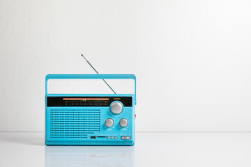 Fototapeta premium Retro old radio receiver light blue with antenna on table in front of white wall in the room