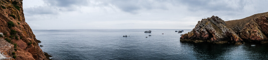 Panoramic view of the coast of the Berlenga Islands in the Atlantic Ocean of Portugal. Cloudy landscape of the Iberian Peninsula. Fishing boats in the water.