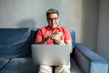 MIddle aged latin man using a smart phone on a couch at home