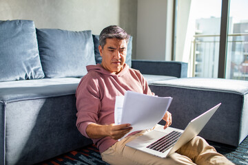 Latin middle aged man going over his home finances and using a laptop