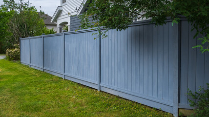 Nice wooden fence around house. Wooden fence with green lawn. Street photo