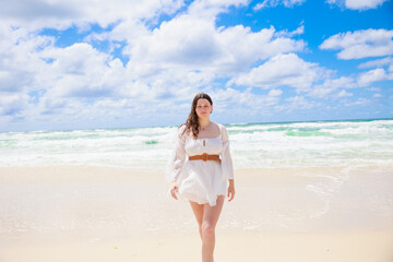 Fototapeta na wymiar 海辺を歩く白いドレスの白人の少女