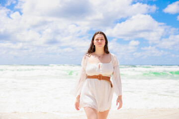 Fototapeta na wymiar 海辺を歩く白いドレスの白人の少女の上半身