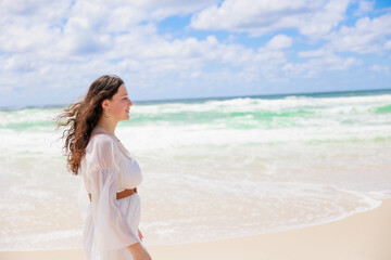 海辺を歩く白いドレスの白人の少女の横顔