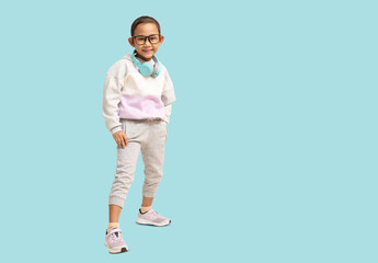 Fototapeta na wymiar School girl, smiling Asian student school kid wearing headphones standing, Full body portrait isolated on pastel plain light blue background