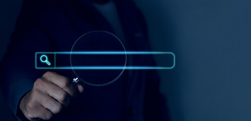 Fototapeta premium Businessman hand using magnifying glass search on virtual screen technology search information search engine optimization Global information search.