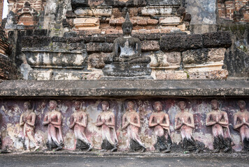 Sculptings of pilgrims on the base of the main chedi in Wat Mahathat temple the most important and impressive temple compound in Sukhothai Historical Park.