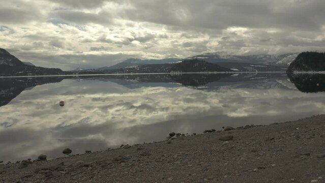 Untouched Wonder: Aerial Footage of Shuswap Lake's Majestic Mountains and Rocky Beach Reflections