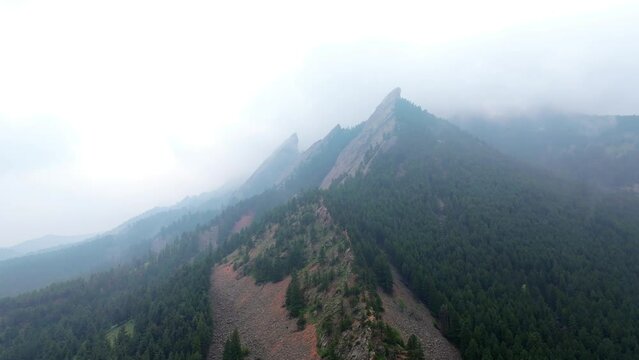 Aerial orbit around flatirons in Boulder, Colorado. Drone establishing shot on misty mountaintop.