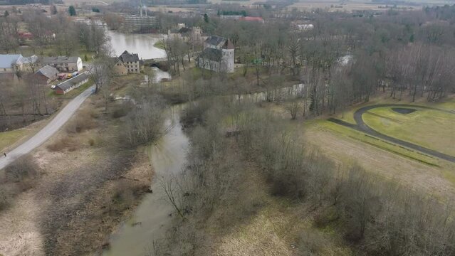 Aerial establishing view of high water in springtime, flood, Durbe river (Latvia), Cirava city, brown and muddy water, sunny day, wide drone shot moving forward