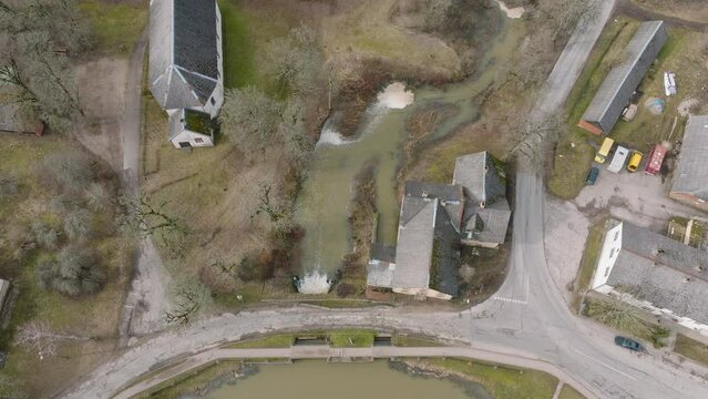 Aerial birdseye view of high water in springtime, flood, Durbe river (Latvia), Cirava city, brown and muddy water, sunny day, wide drone shot moving forward