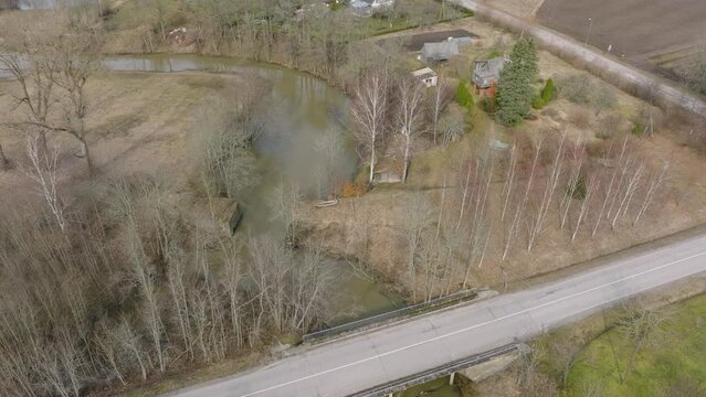 Aerial establishing view of high water in springtime, flood, Durbe river (Latvia), Cirava city, brown and muddy water, sunny day, wide drone shot moving forward
