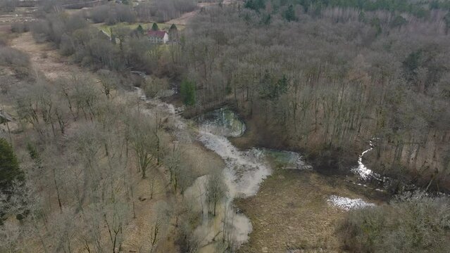 Aerial establishing view of high water in springtime, flood, Durbe river (Latvia), Cirava city, brown and muddy water, sunny day, wide drone birdseye shot moving forward