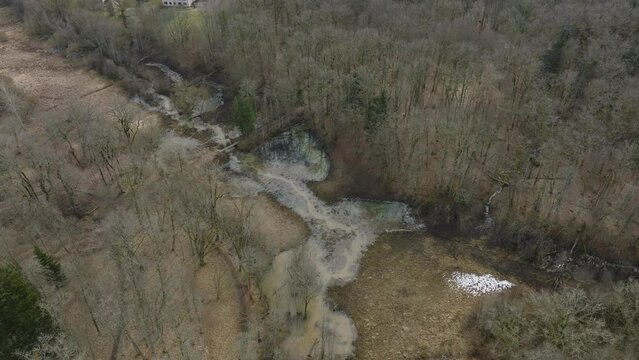 Aerial establishing view of high water in springtime, flood, Durbe river (Latvia), Cirava city, brown and muddy water, sunny day, wide drone shot moving backward