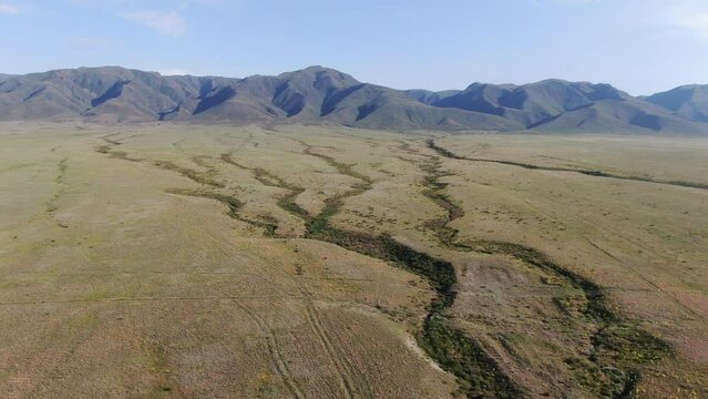 This stock video shows a summer mountain landscape: mountains, dehydrated streambeds, sparse vegetation. This video will decorate your projects related to nature, weather, summer landscapes, travel.