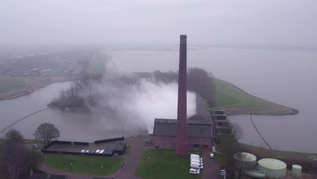 Drone flying around Woudagemaal steam pumping station during cloudy sunrise, Aerial