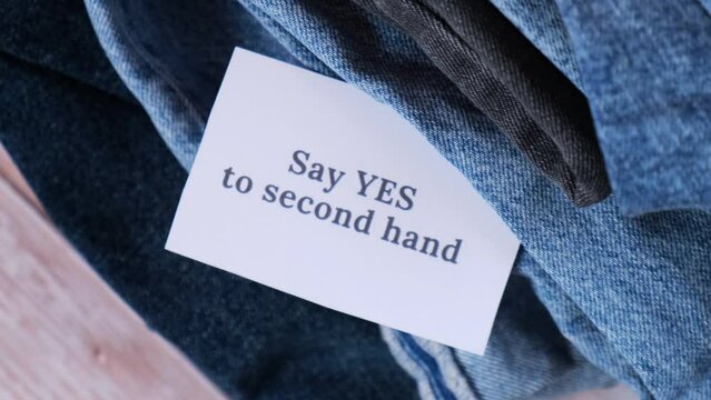 SAY YES TO SECOND HAND text on paper note on Jeans clothes assortment Second hand sustainable shopping. Capsule minimal wardrobe. Sustainable fashion overconsumption, conscious buying consumption
