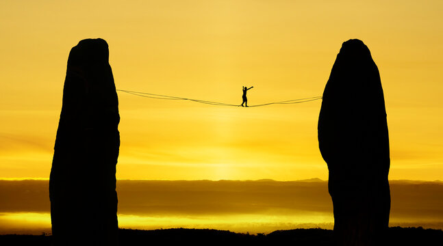 Silhouette of tightrope walker balancing on the rope