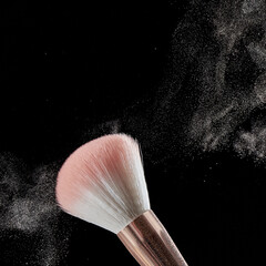Make-up brush with powder on it and heap of powder on black background. Photo with copy space.