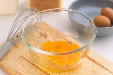 Woman beating eggs in a glass bowl. Young woman cooking in the kitchen.
