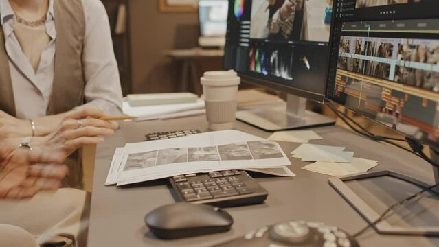 Focus on hands of female Caucasian manager and male unrecognizable coworker having project discussion in loft office in evening