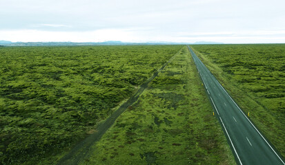 Aerial view of the beautiful northern road in the middle of the green field of Iceland. Photography for tourism background, design and advertising