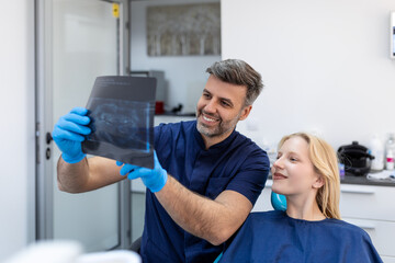 Doctor talking with her patient and teaching a radiograph. Dentist concept of woman sitting in a dental chair while her dentist reads out an x-ray scan