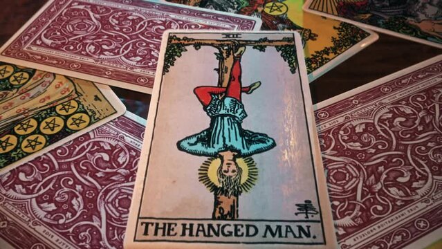 Paris, France - January 5, 2017. Reading the mysterious Hanged Man tarot card for a spell. Mysterious card for spiritual spells shows upside-down person. Mysterious spell card depicts man on a cross.