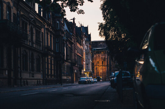 Trier during sunset. Early evening. Empty main street lined with parked cars in the city.