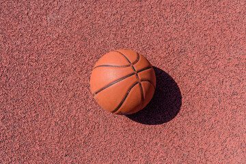 Basketball ball lying on the rubber sport court.Sport red ground outdoor.Top view,Copy...