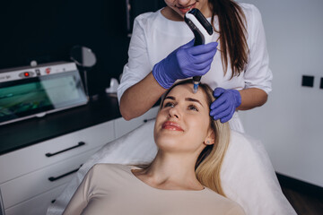 Close up of beautician hands in sterile gloves using dermapen during skincare procedure. Young...