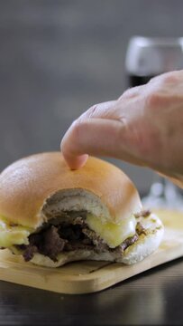 Barros Luco placing sandwich with snack. popular in Chile: meat with melted cheese, glass of red wine, on vertical black wooden table, with space to copy concept of typical Chilean food