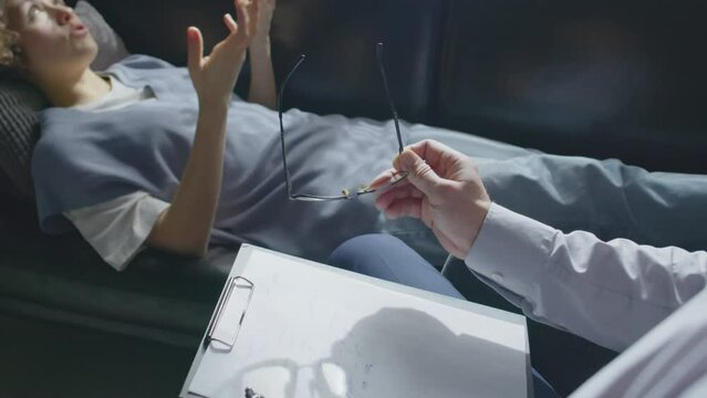 Selective focus high angle shot of mature male psychologist working with young woman with depression or post-traumatic disorder