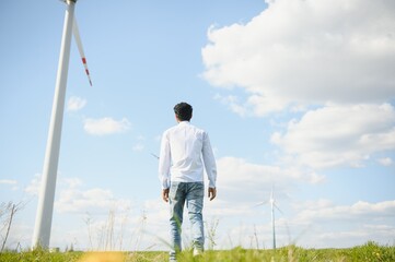 India engineer at windmill farm operation to generate electricity, Asian man working at wind turbine farm, Clean and green energy.