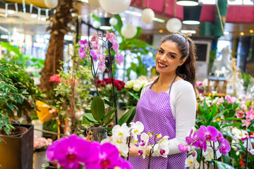 Proud and beautiful florist poses for the camera holding her beautiful and well-groomed orchids