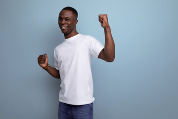 positive attractive young american guy in white t-shirt smiling on studio background with copy space