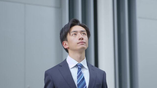 遠くを見つめるスーツを着た若い日本人ビジネスマンのスローモーションイメージ