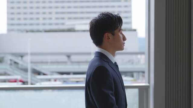 スーツを着て歩く若い日本人ビジネスマンのスローモーションイメージ