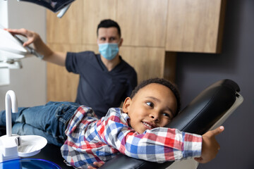 Dark-skinned kid lying on the chair at dentists office