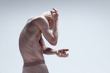 Dreaming blond man covering face with hands isolated over white studio background. Model posing like antique sculpture. Male body aesthetics, men's beauty
