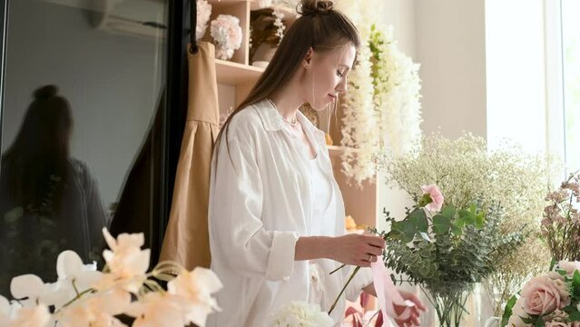 A woman florist is working hard in a flower shop. Floral design studio, making decorations and arrangements. Flower delivery, order creation. Small business.