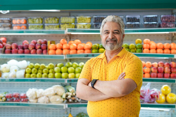 Senior indian man standing at fruit shop. Healthy lifestyle concept.