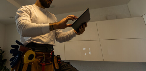 A worker looks at a tablet computer. Master with an electronic tablet in his hands