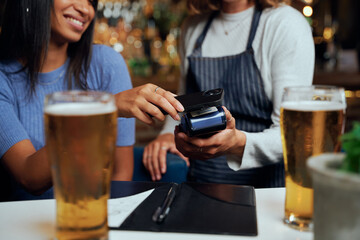 Young woman in casual clothing paying for dinner with wireless technology next to waitress