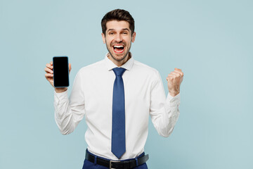 Young winner employee business man corporate lawyer in classic formal shirt tie work in office hold use blank screen workspace area mobile cell phone isolated on plain blue background studio portrait.