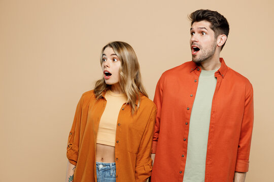 Young shocked surprised amazed impressed couple two friends family man woman wear casual clothes looking aside on area together isolated on pastel plain light beige color background studio portrait.