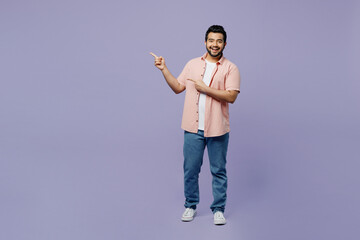 Full body fun young Indian man he wear pink shirt white t-shirt casual clothes point finger aside...