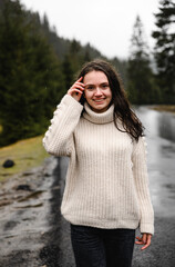 portrait of a young woman in the rain on an asphalt road in a mountainous area