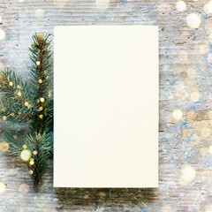 Christmas still festive life. Blank invitation mockup on old wooden background. Fir branches on the table. Copy space, top view.	