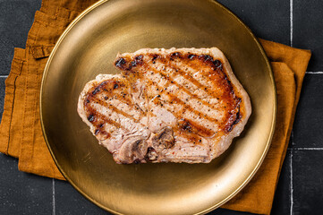 BBQ fried pork T bone chop meat steak on a plate. Black background. Top view